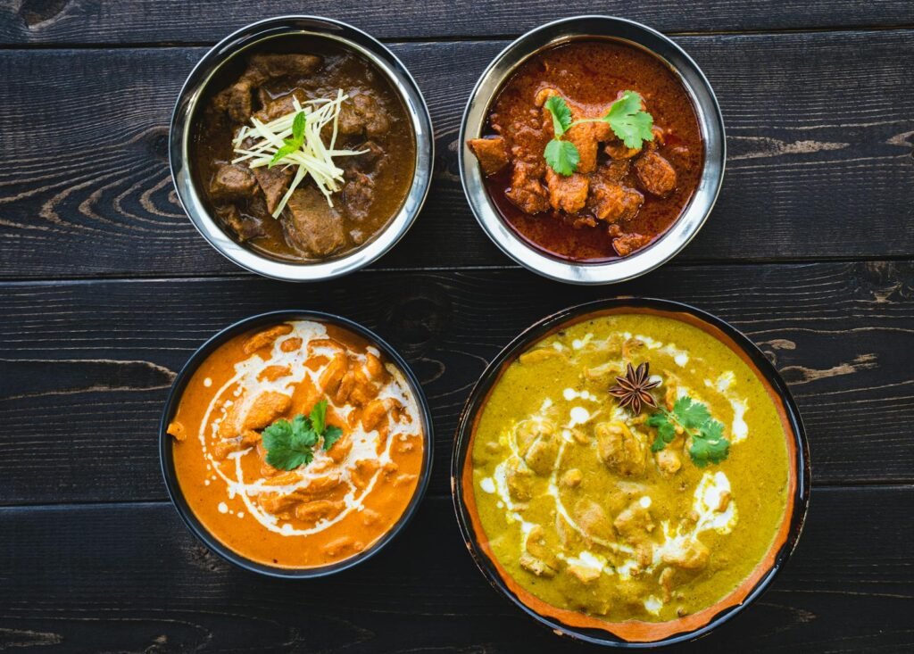 Vibrant Indian curries in bowls on a dark rustic table, ideal for food enthusiasts.