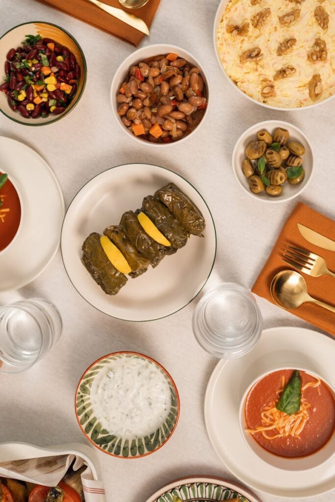 A top-down view of a Mediterranean meal spread featuring diverse dishes like lentil soup and stuffed grape leaves.