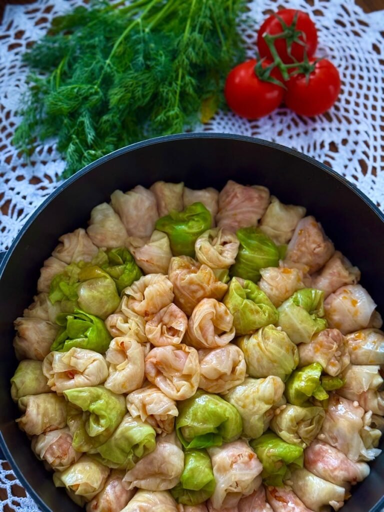 Freshly prepared stuffed cabbage rolls with dill and tomatoes garnish.