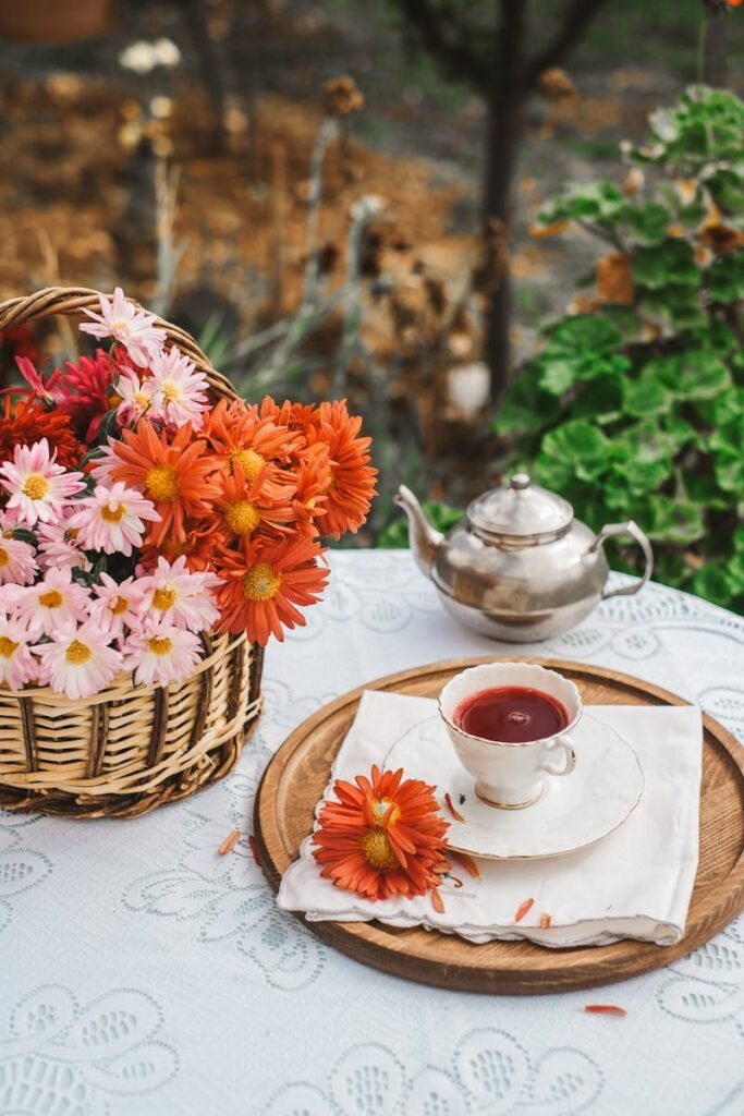 Elegant tea setting in a garden with a basket of vibrant flowers and classic teapot.