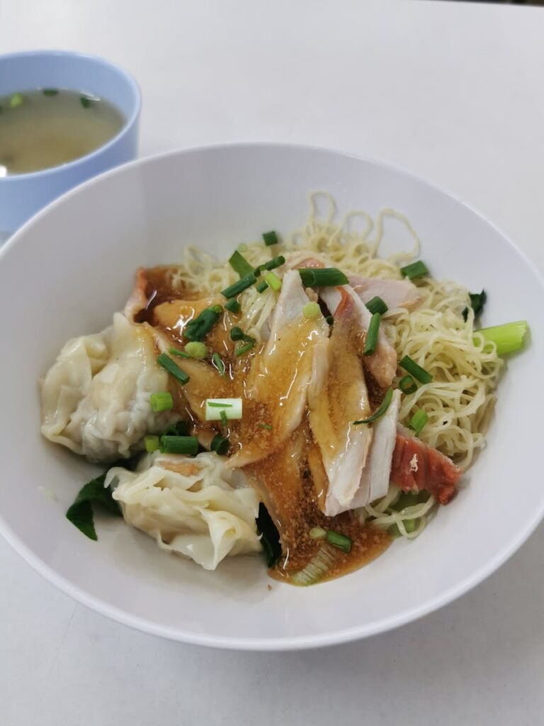 Tasty Asian noodle dish with chicken and dumplings, garnished with fresh herbs.