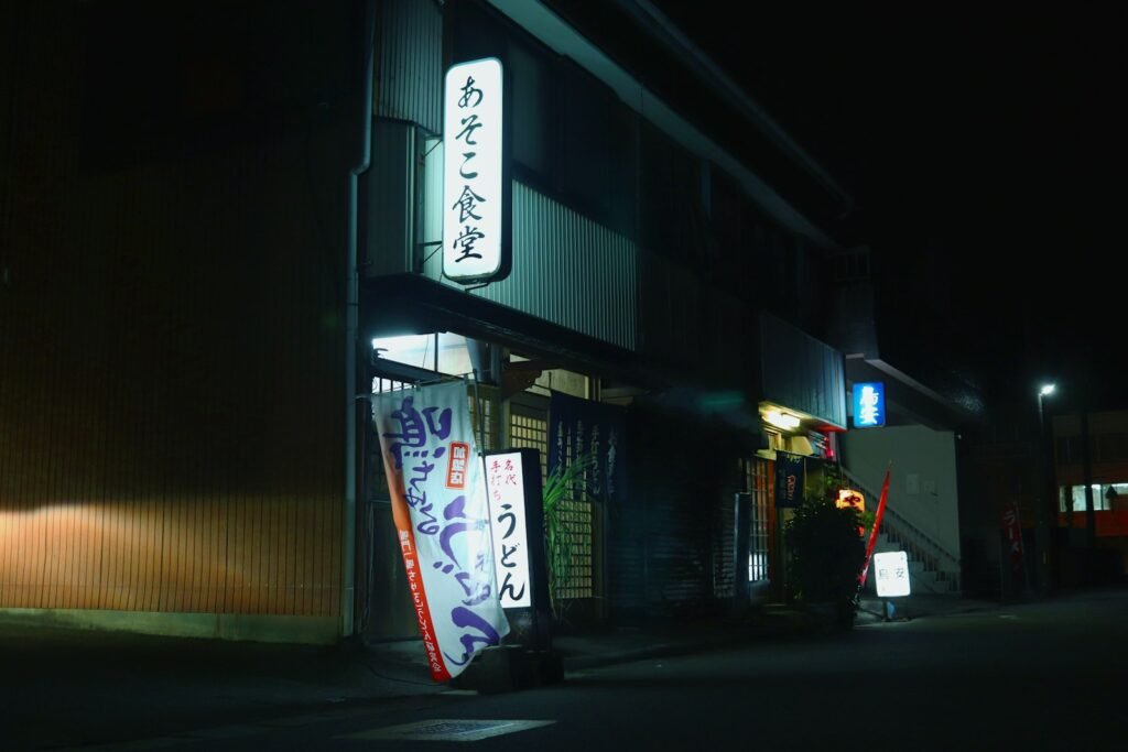 A dark street at night with a store front lit up