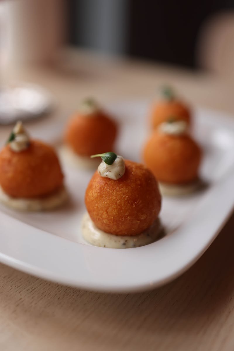 Close-up of risotto arancini with sauce on a white plate, perfect appetizer.