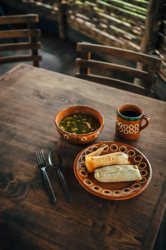 Mexican tamales and soup served on a wooden table, creating an authentic dining experience.