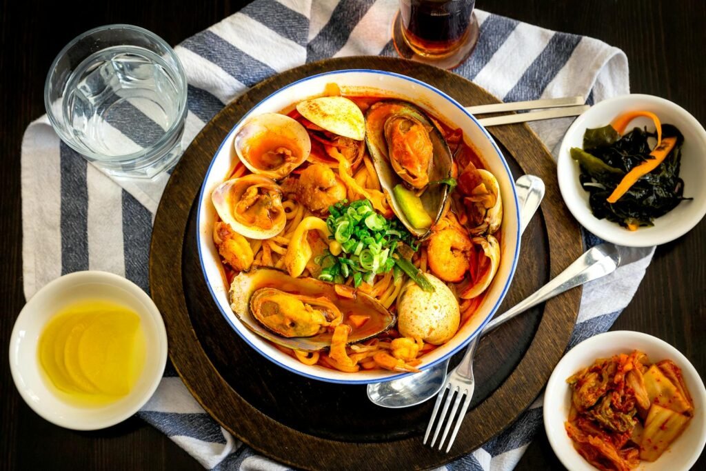 A vibrant Korean seafood noodle dish with side dishes, perfect for a hearty meal.