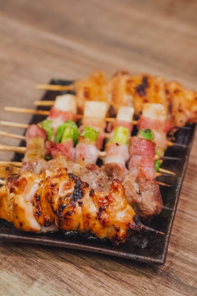 A plate of assorted yakitori skewers including chicken and vegetables.