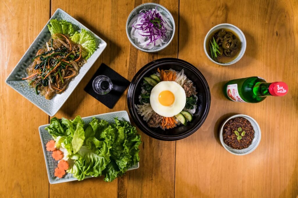 Overhead view of assorted Korean dishes featuring bibimbap, reflecting authentic Asian culinary style.