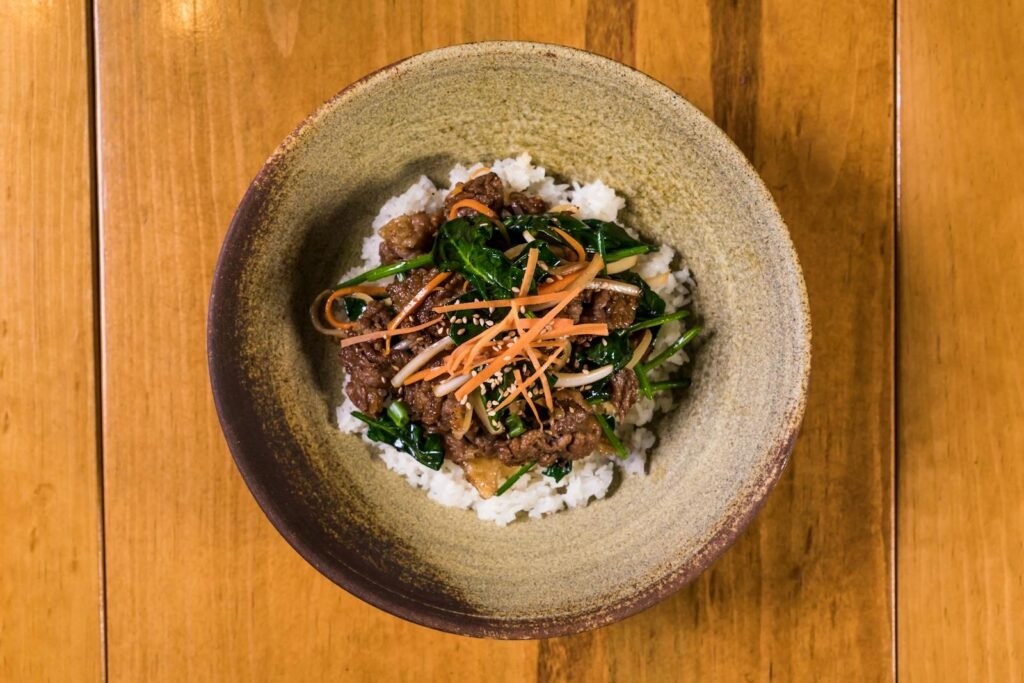 A flavorful Korean bulgogi rice bowl presented in an artistic top view on a wooden table.