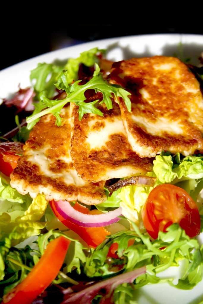 A white plate topped with a salad and meat
