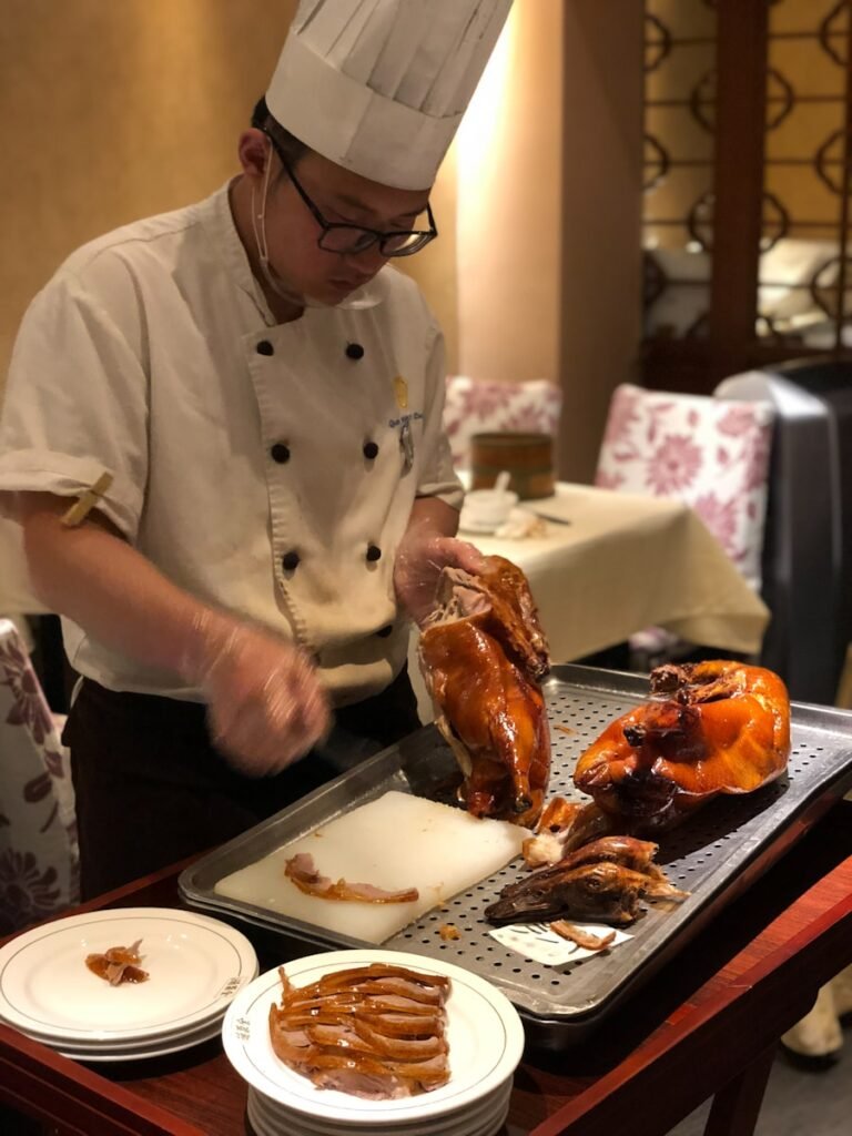 man in white chef uniform holding a cooked chicken