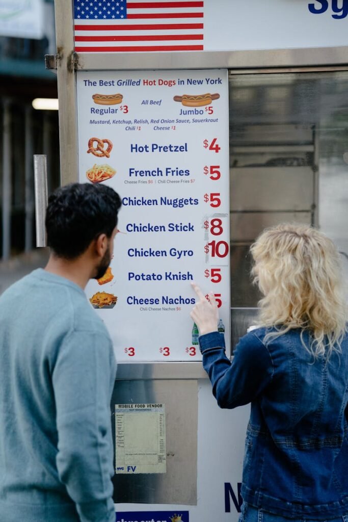 A couple decides on a meal from a food truck menu in New York City, featuring various snacks.