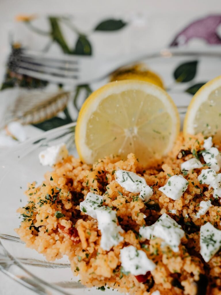 A vibrant dish featuring couscous topped with feta cheese and fresh lemon slices, perfect for a fresh, homemade meal.