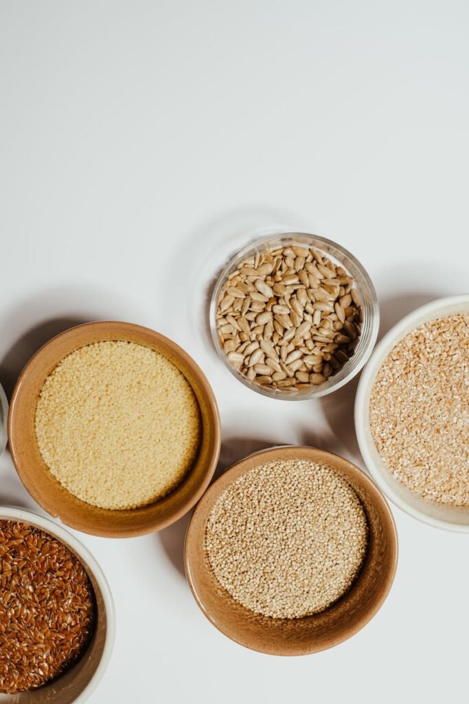 Aerial view of assorted healthy grains and seeds in bowls, highlighting nutrition and simplicity.